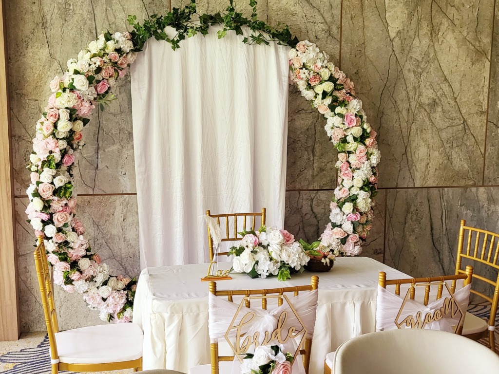 Signature solemnisation setup with floral arch table skirting and Tiffany chairs by Zeaflora