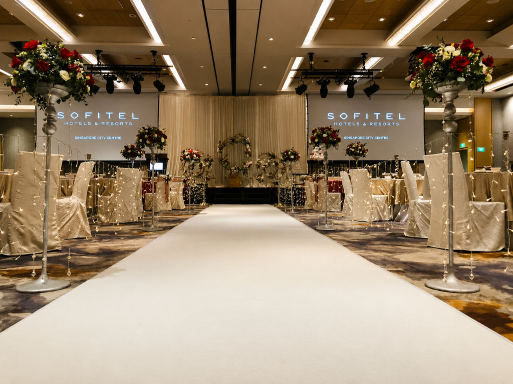 Elegant wedding aisle carpet surrounded by white floral decorations and warm venue lighting